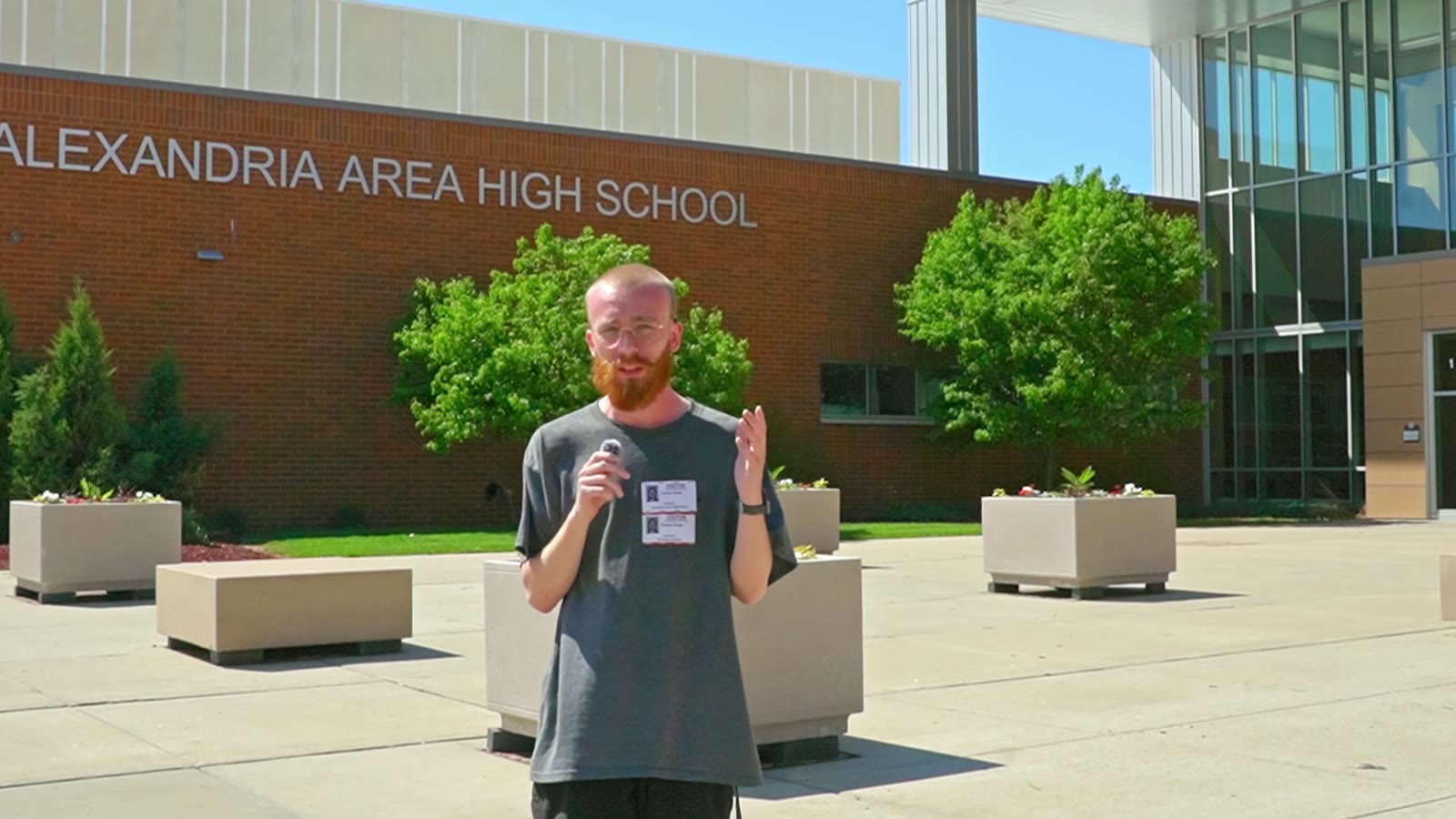 Film still showing a presenter outside Alexandria Area High School.